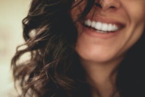 Close-up photo of a woman smiling. She has lovely white teeth straight.