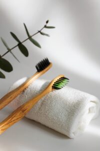 Two tooth brushes resting on a rolled up white towel