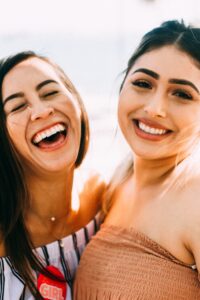 Two ladies smiling together after receiving cosmetic dentistry treatments